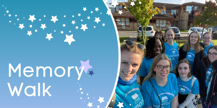 Group of Miscarriage Association fundraisers in blue Memory Walk t-shirts smiling together outdoors, with banner text 'Memory Walk' and star graphics